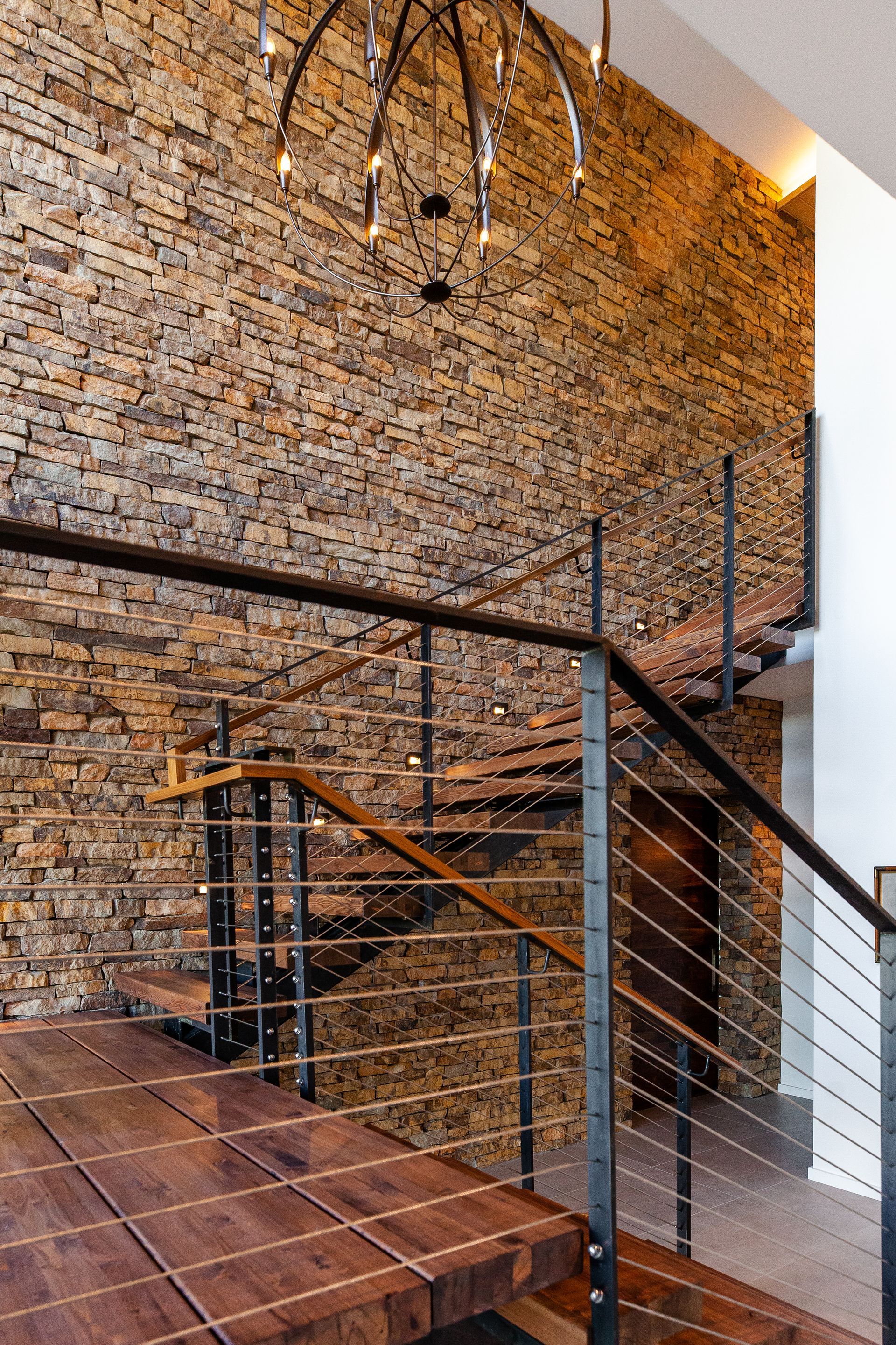 A wooden staircase with a metal railing in front of a brick wall.