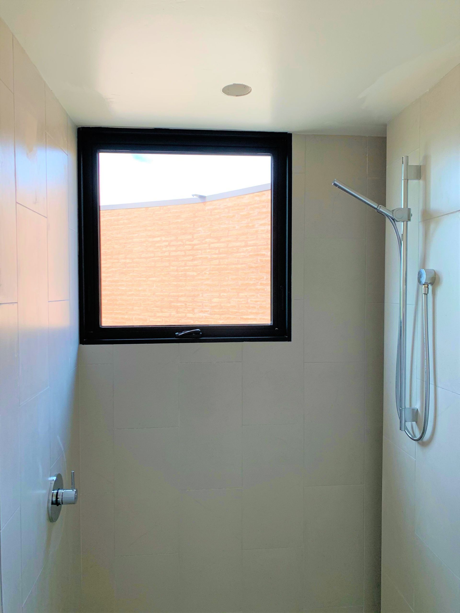 A bathroom with a shower and a window.