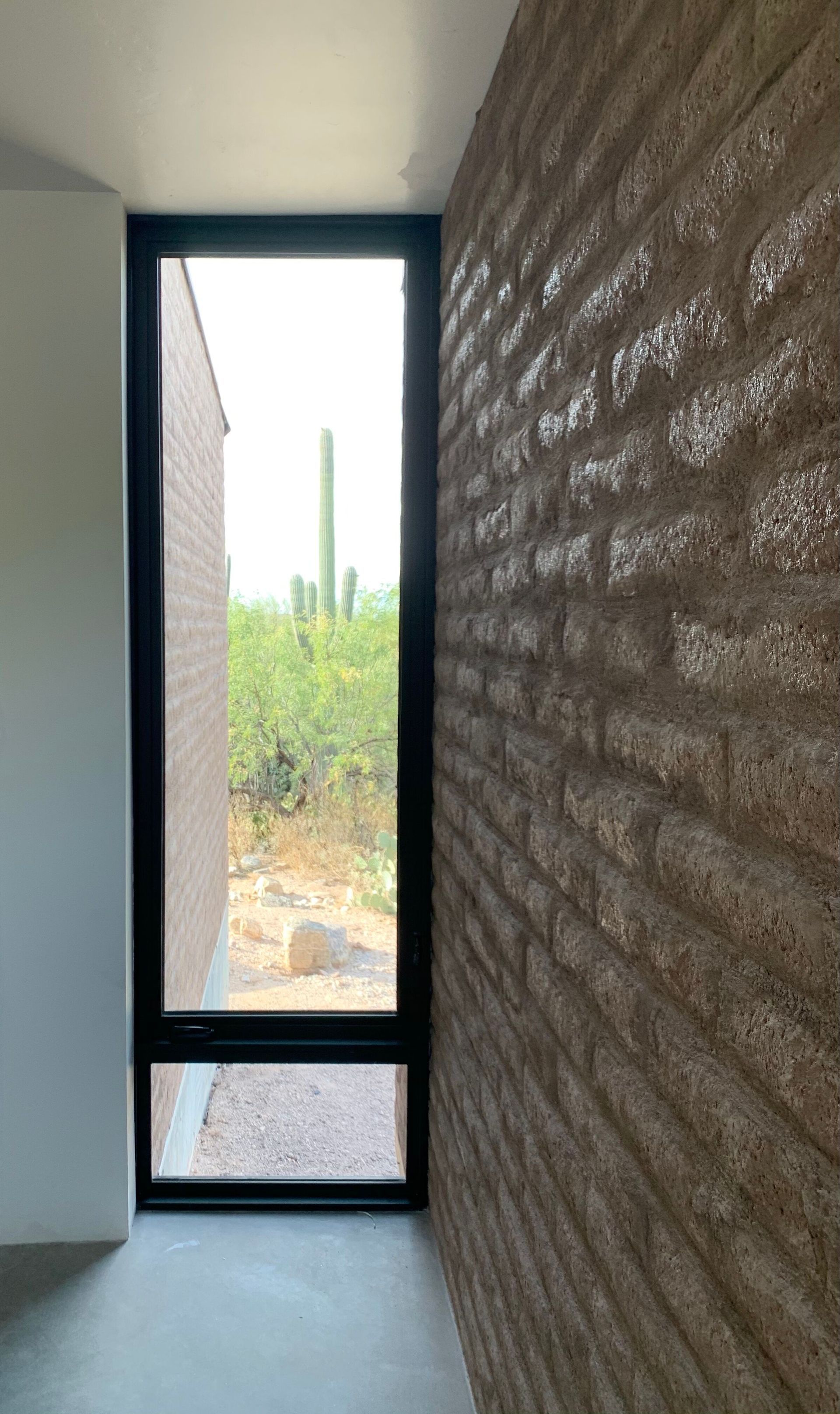 A hallway with a brick wall and a large window.