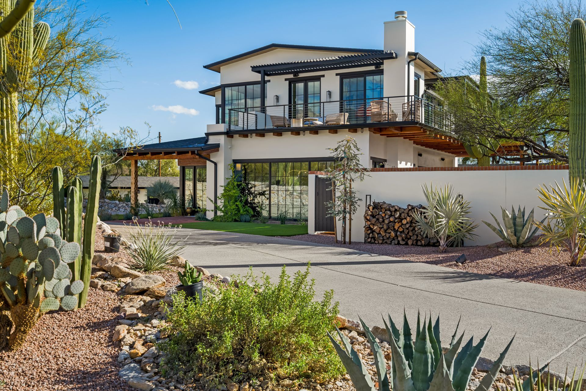 A large white house is surrounded by cactus and plants.
