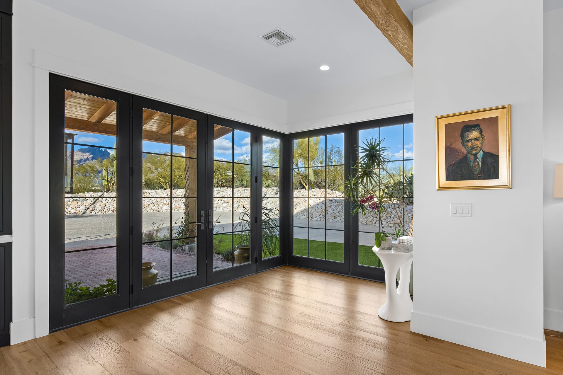 A room with a lot of windows and a painting on the wall.