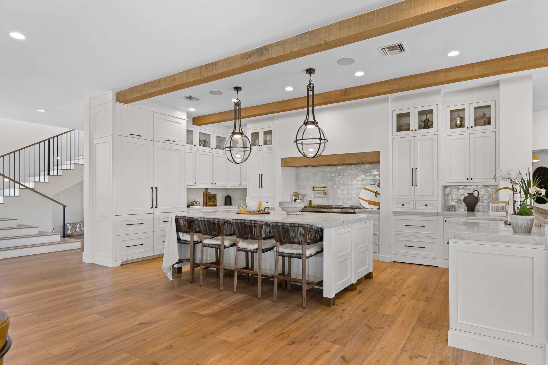 A kitchen with white cabinets and wooden floors and a large island.