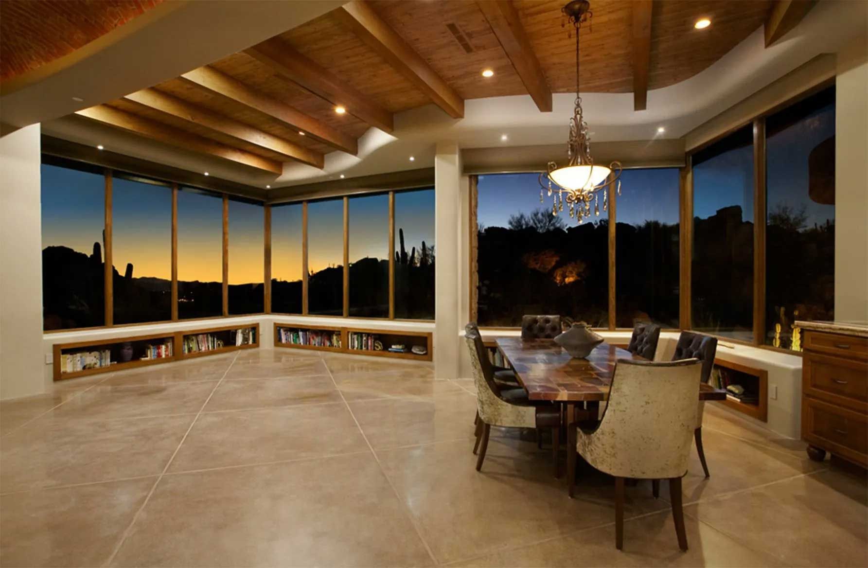 A dining room with a table and chairs and lots of windows