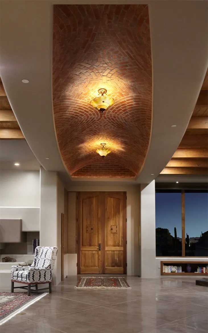 A living room with a wooden door and a ceiling with lights