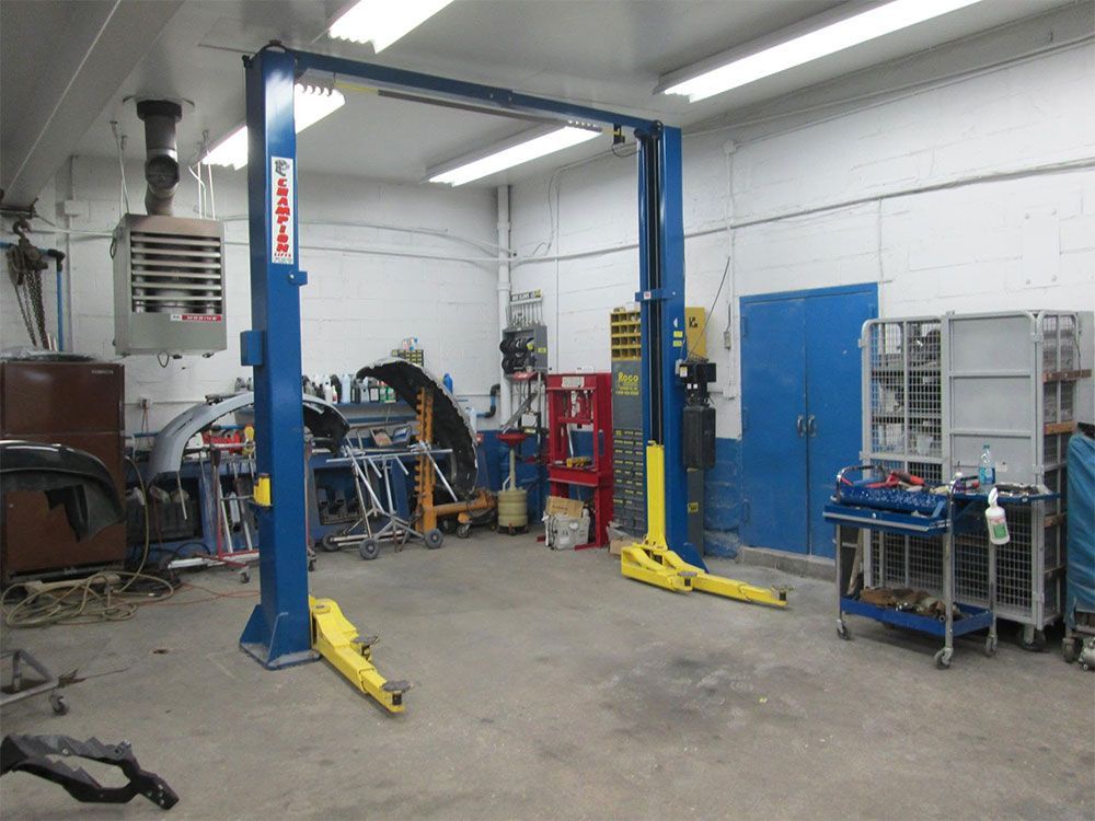 Auto repair shop interior with two blue car lifts, tools, and workbenches