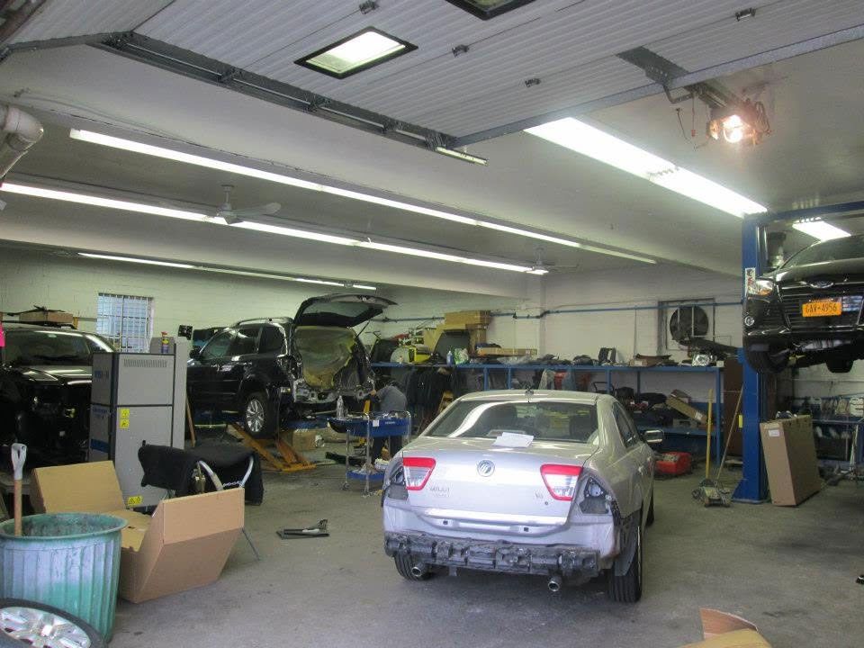 Auto repair shop interior with cars, tools, and equipment scattered around the garage.