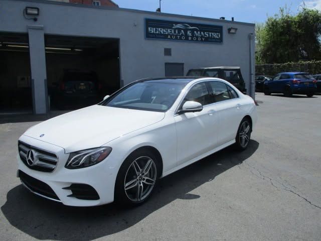 White Mercedes sedan parked outside a building in a sunny lot