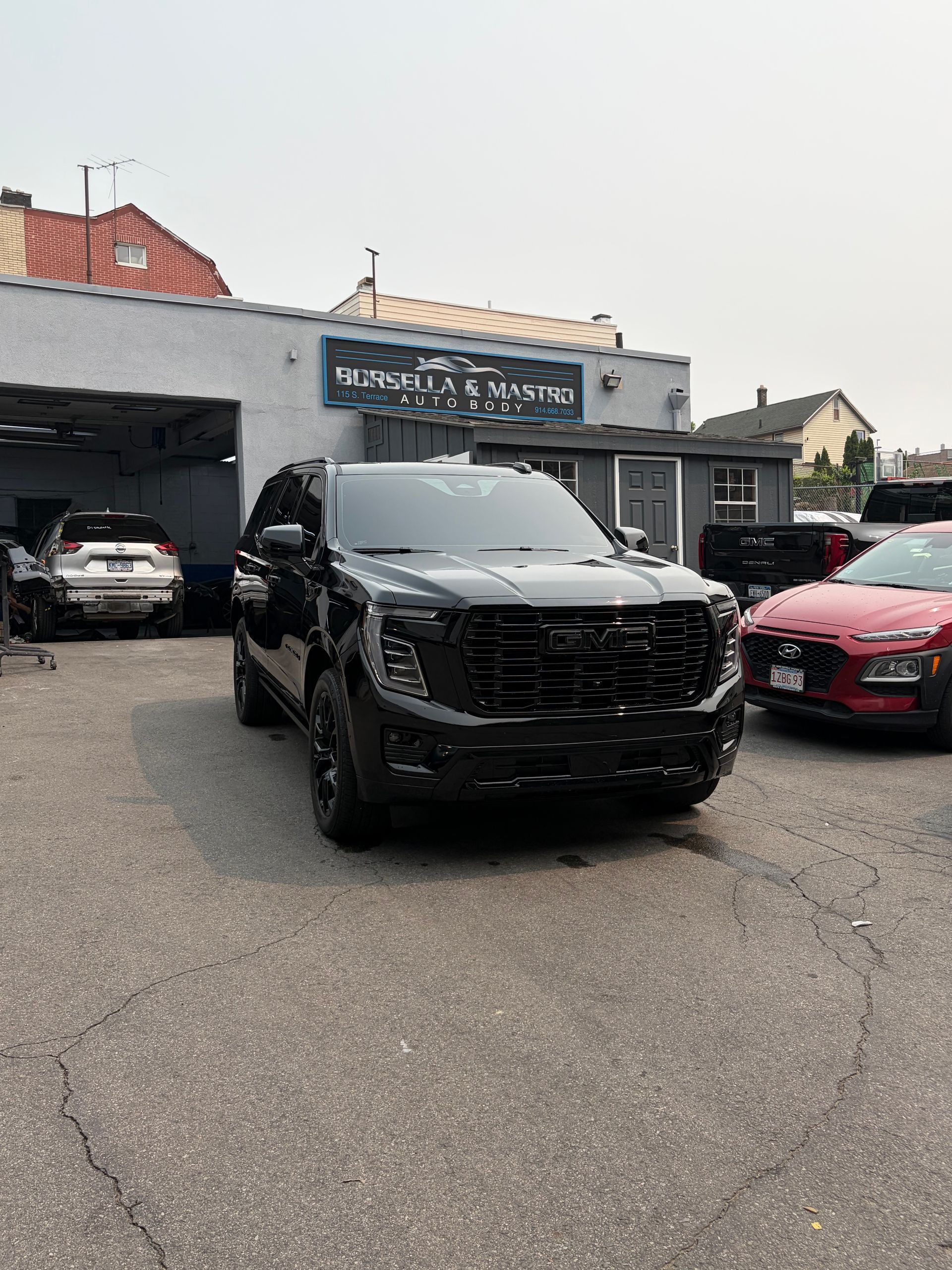 Black SUV parked outside a car dealership, with other vehicles and storefronts in the background.