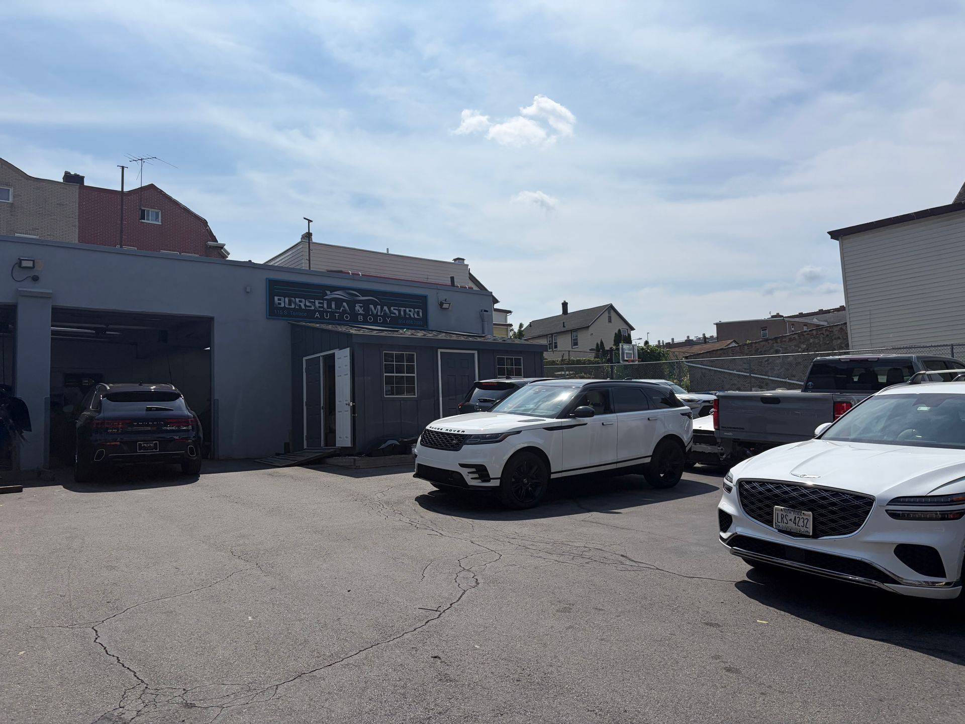Parking lot with several cars beside a low building under a bright blue sky.