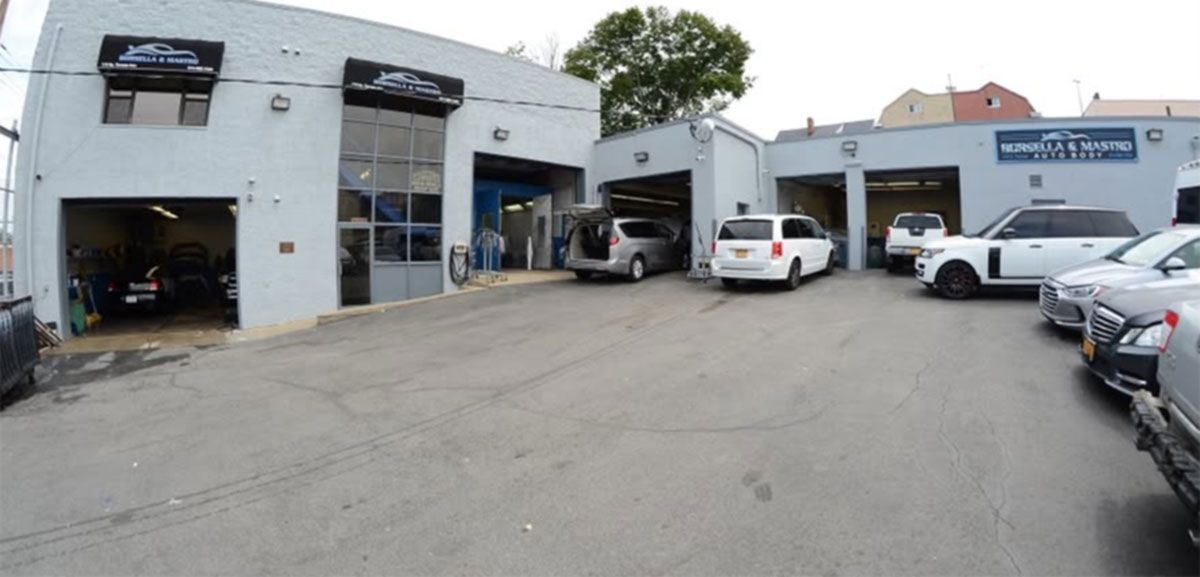 Auto repair garage with multiple cars parked outside in a service lot