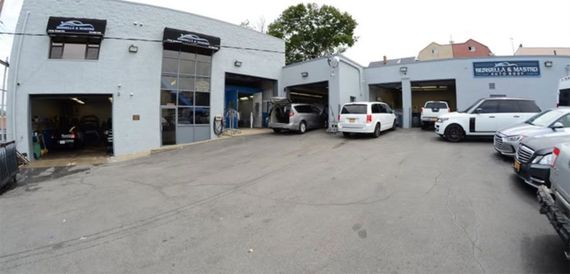 Auto repair garage with multiple cars parked outside in a service lot