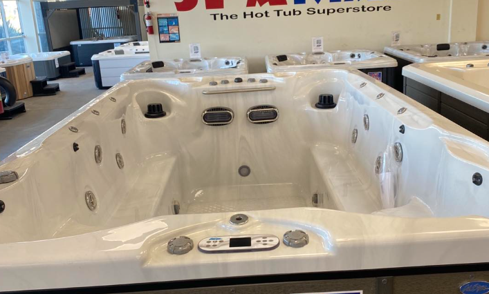 White hot tub in a showroom with multiple hot tubs displayed in the background.