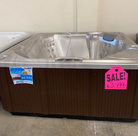 A brown, rectangular hot tub with a metallic interior and a bright pink 