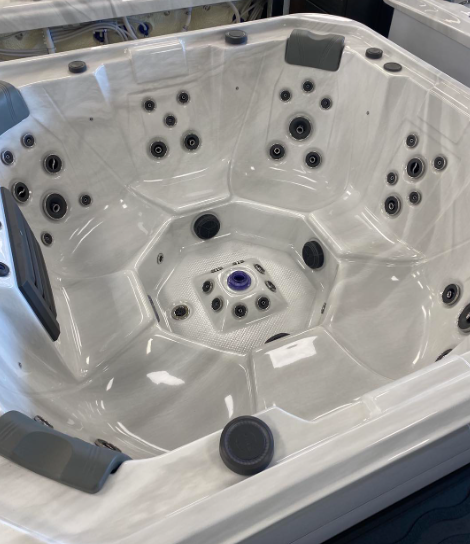 A white, square hot tub with multiple jets, seating areas, and dark grey headrests, viewed from above.