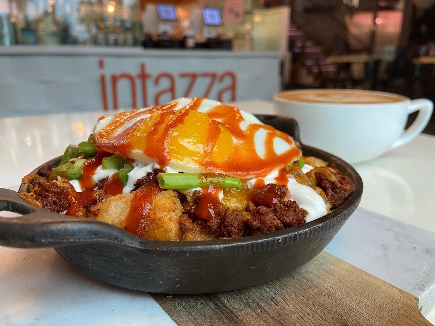 A skillet filled with food and a cup of coffee on a table.