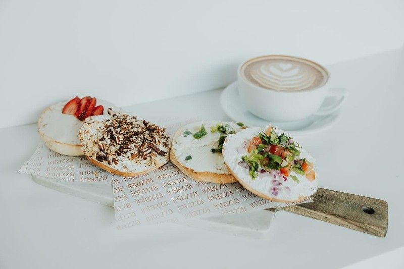 A tray of bagels and a cup of coffee on a table.