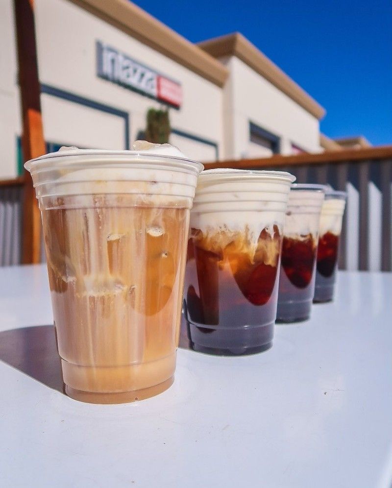 A row of cups on a table in front of a pizza hut