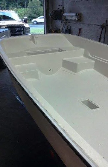 A white, empty small boat inside a garage.