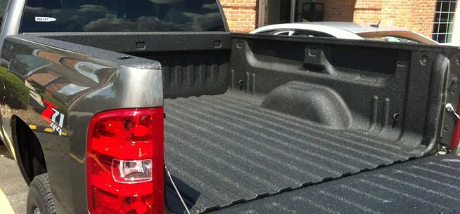 Close-up of the bed of a pickup truck with a black bed liner.