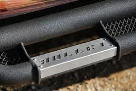Close-up of a black bumper with a silver step that reads
