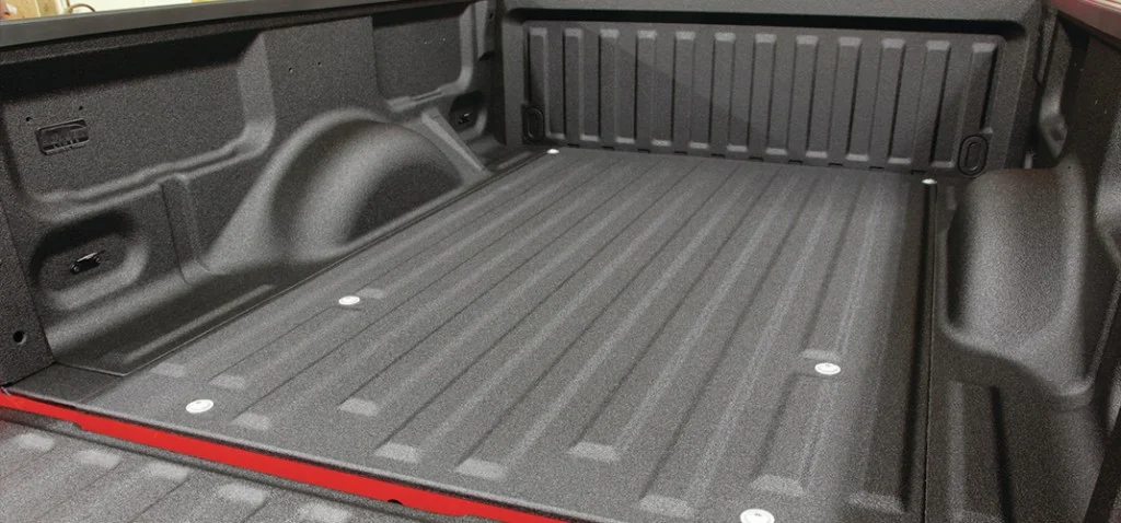 Empty, black truck bed with textured surface and tie-down points.