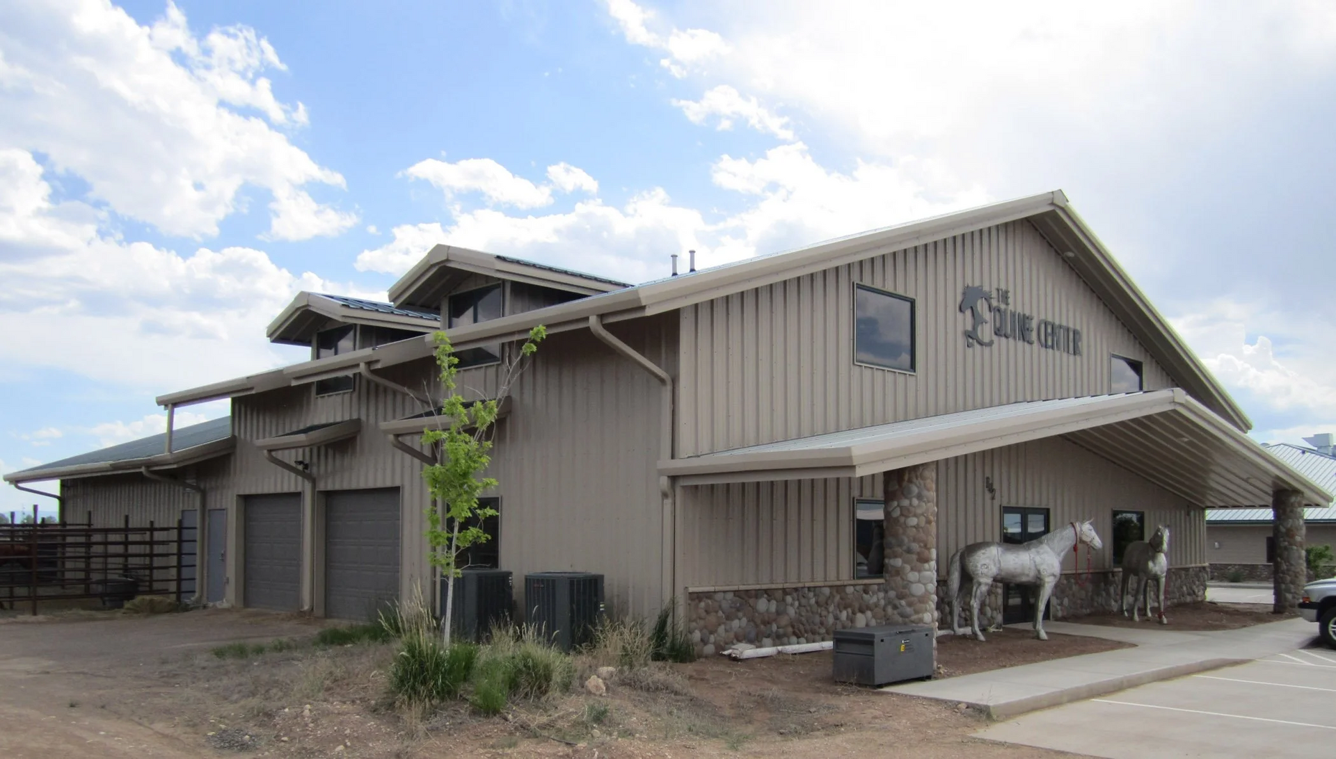 Tan building with a stone facade, a white horse statue, and the name