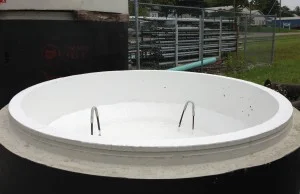 Open, white-lined tank with two metal handles; black exterior, outdoor setting.