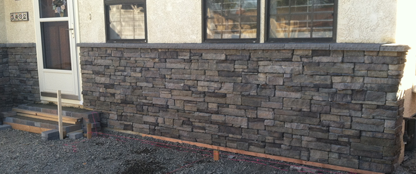 Stone veneer being installed on a home's facade, framing the front door and windows.