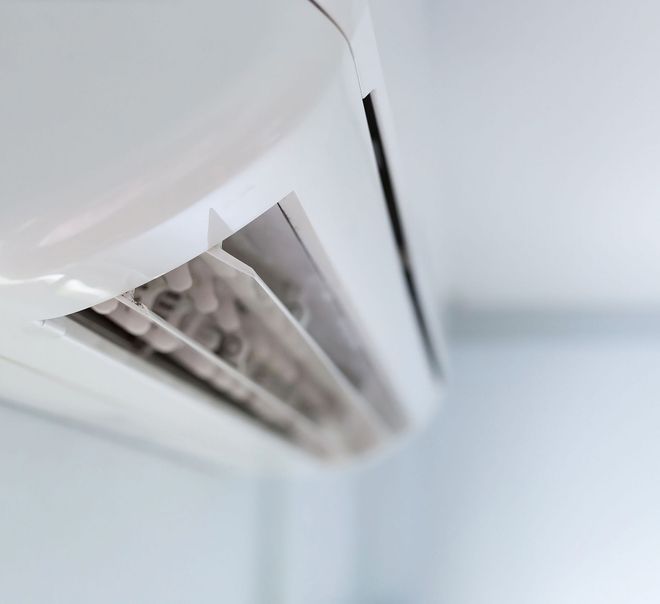 Close-up of a white wall-mounted air conditioner vent with angled louvers