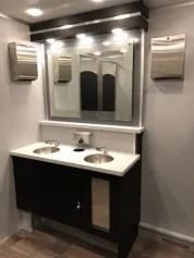 Modern bathroom vanity with double sinks, large mirror, and wall-mounted soap dispensers
