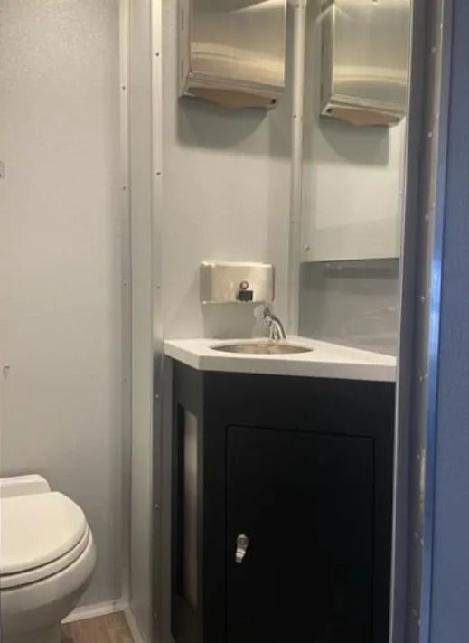 Small bathroom vanity with sink, mirror, soap dispenser, and toilet visible on the left.