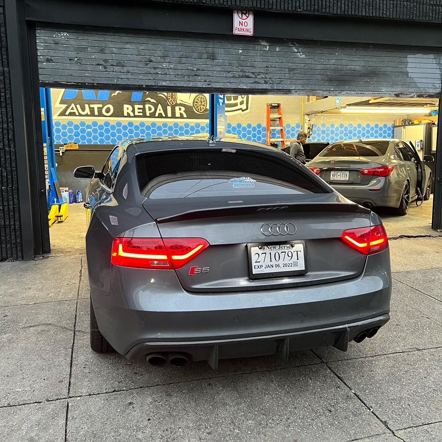 A gray audi is parked in front of an auto repair shop.