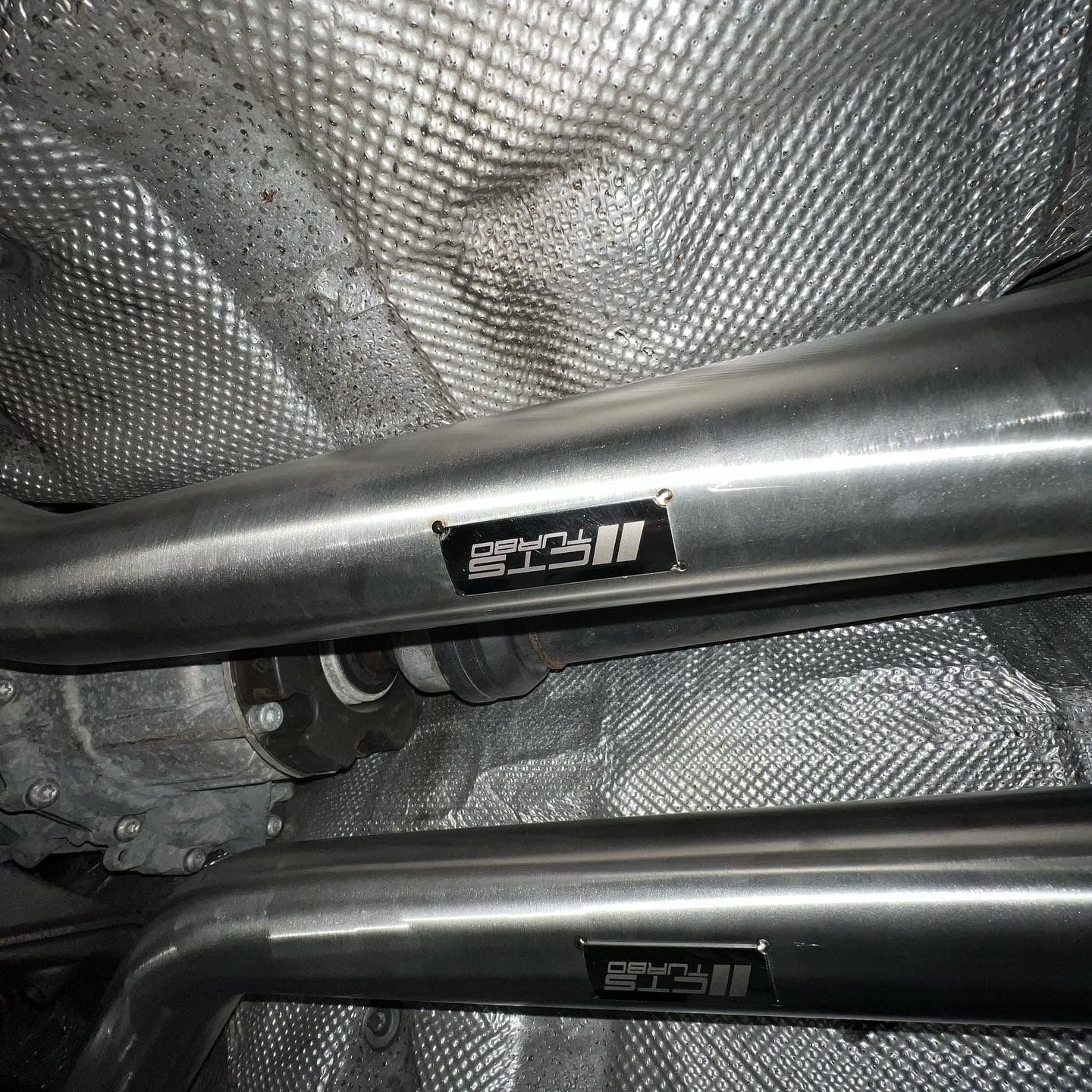 A close up of a metal pipe under a car.