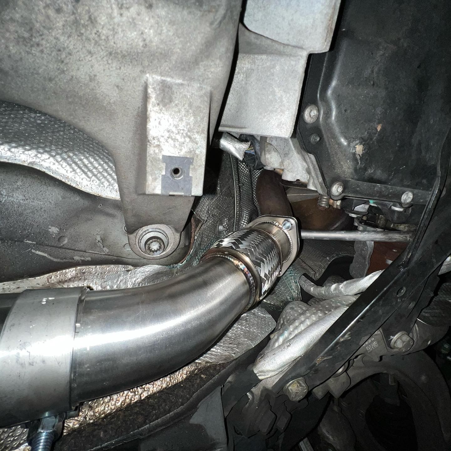 A close up of a stainless steel pipe under a car