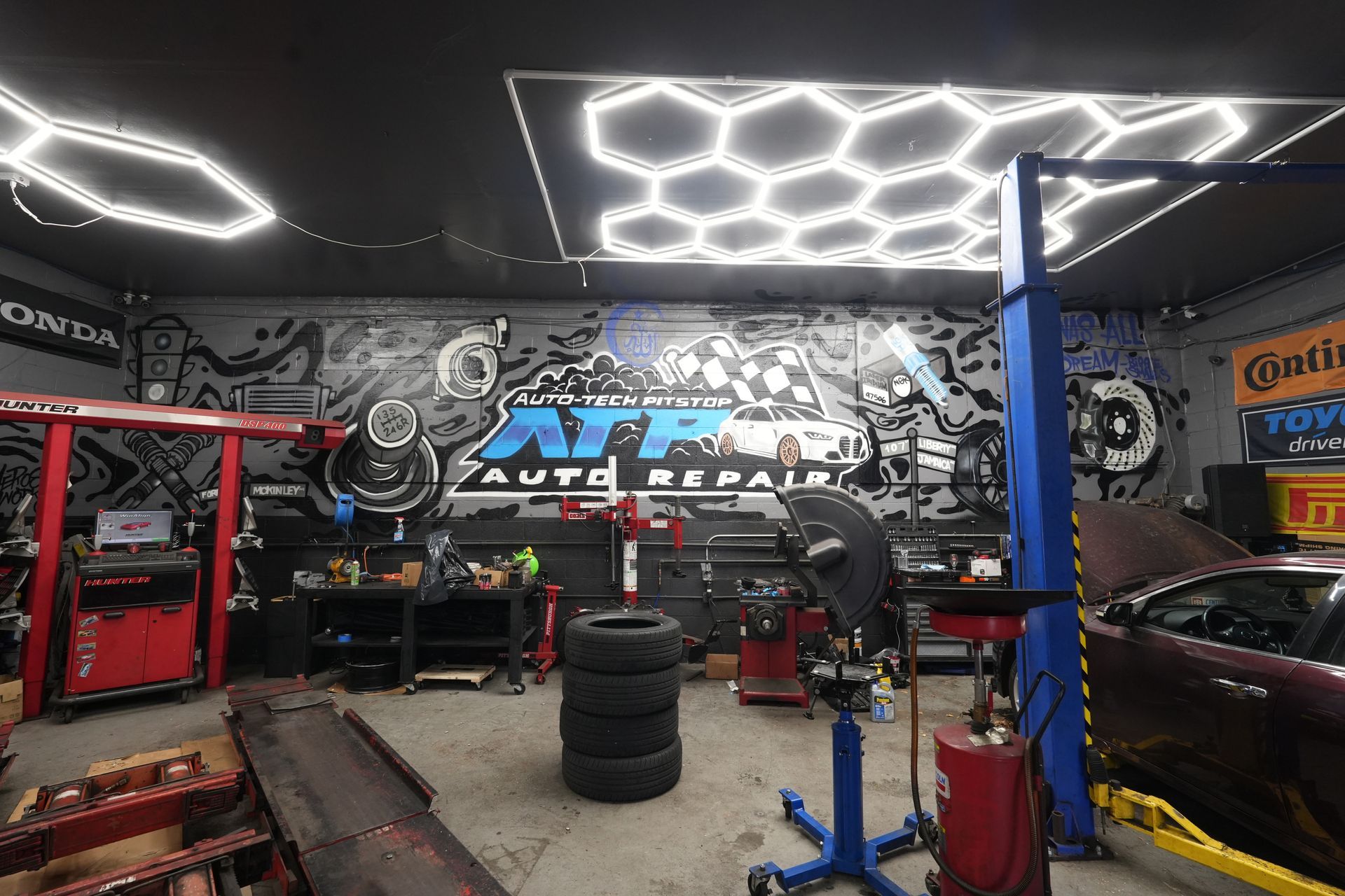 A garage with a stack of tires and a car on a lift.