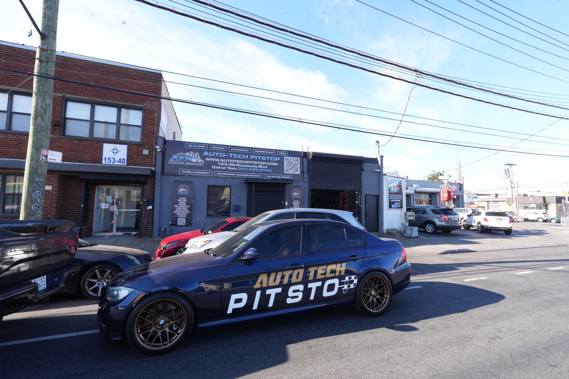 A car is parked in front of a building that says auto tech pit stop.