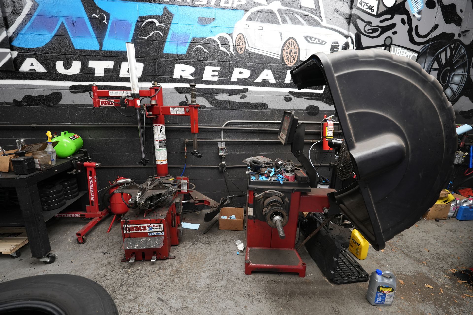 A tire balancing machine is sitting in front of a wall that says auto repair