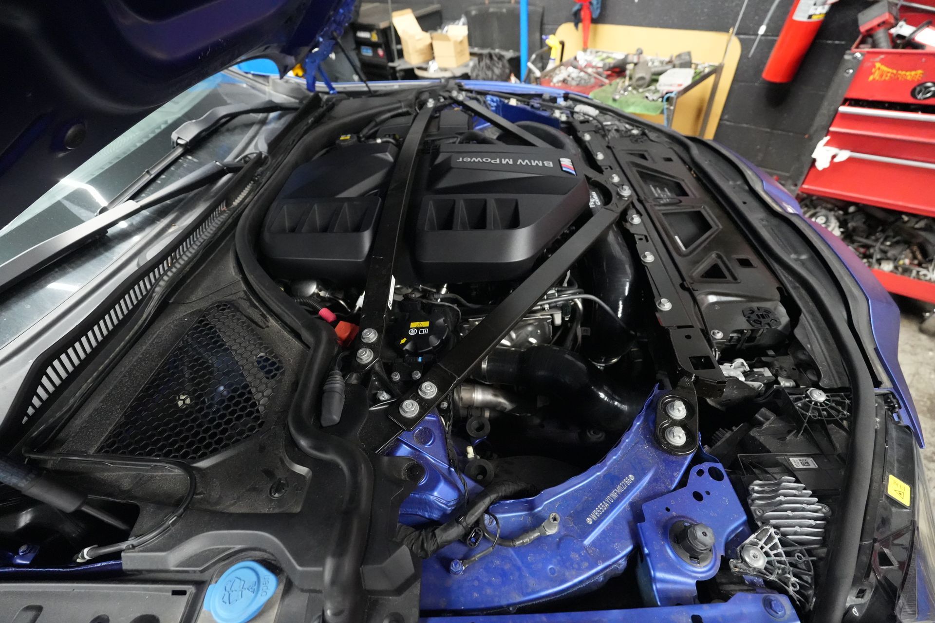 A close up of the engine of a car with the hood open.