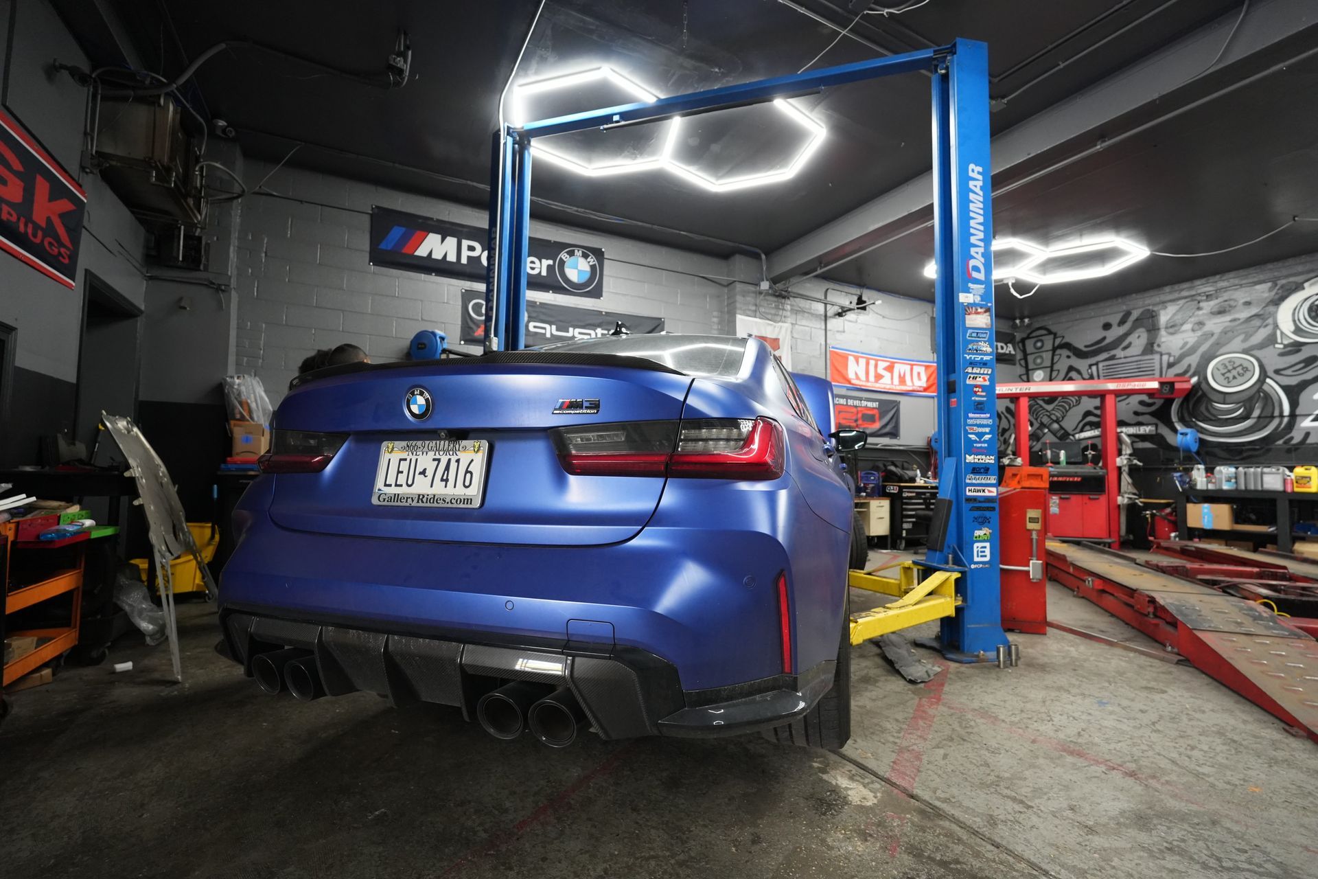 A blue bmw is sitting on a lift in a garage.