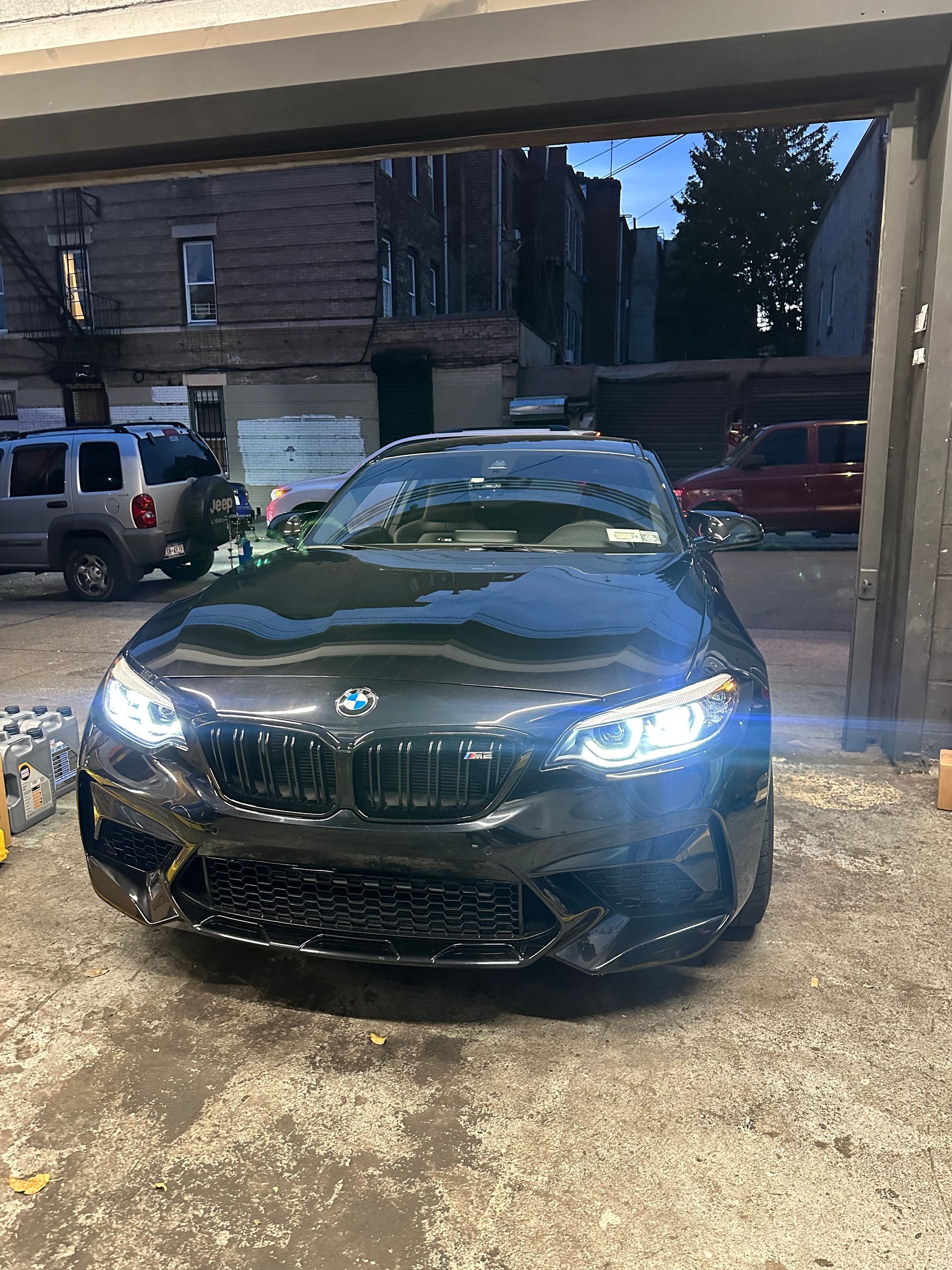 A black bmw m2 is parked in a garage.