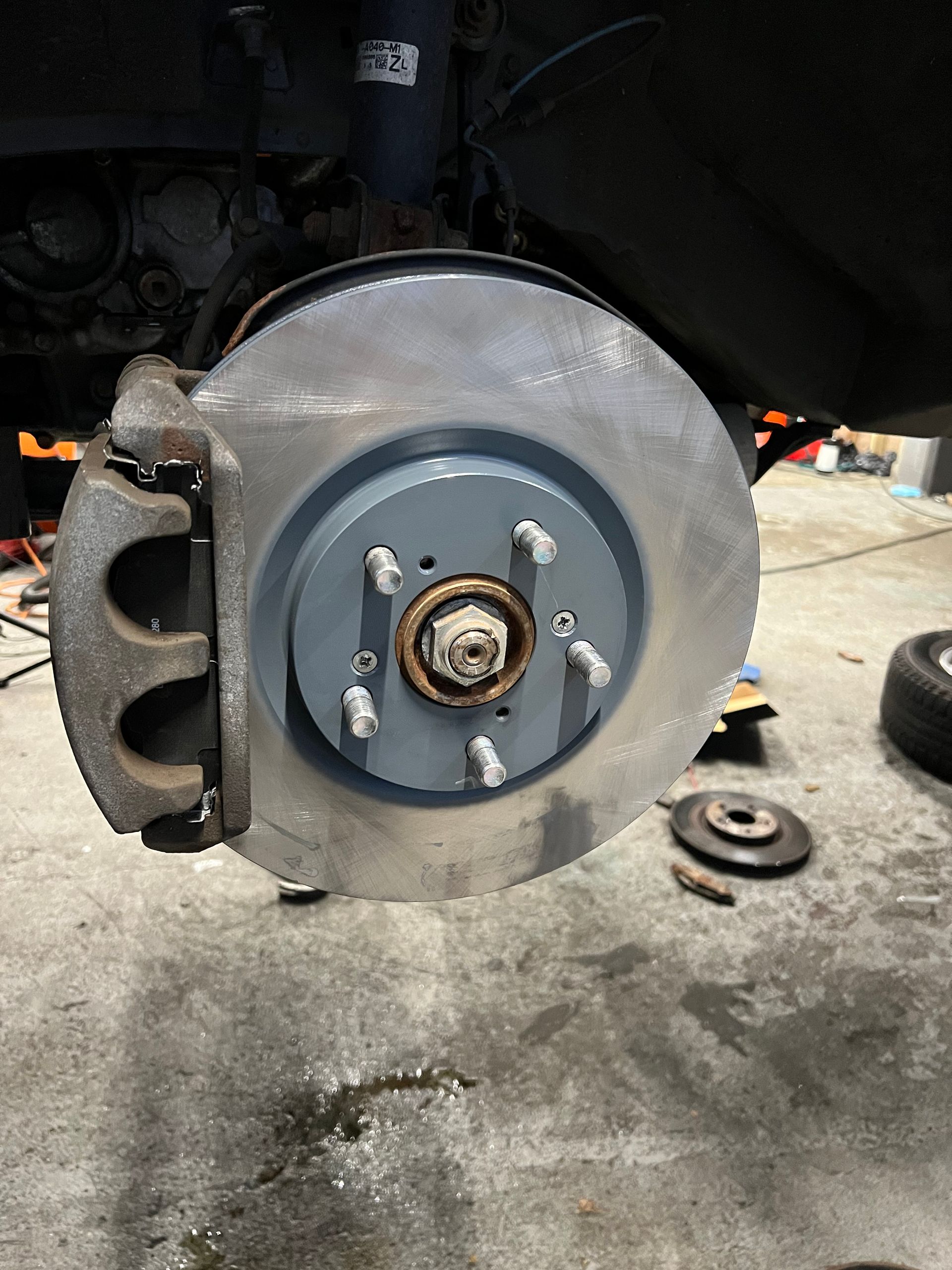 A close up of a brake disc on a car in a garage.