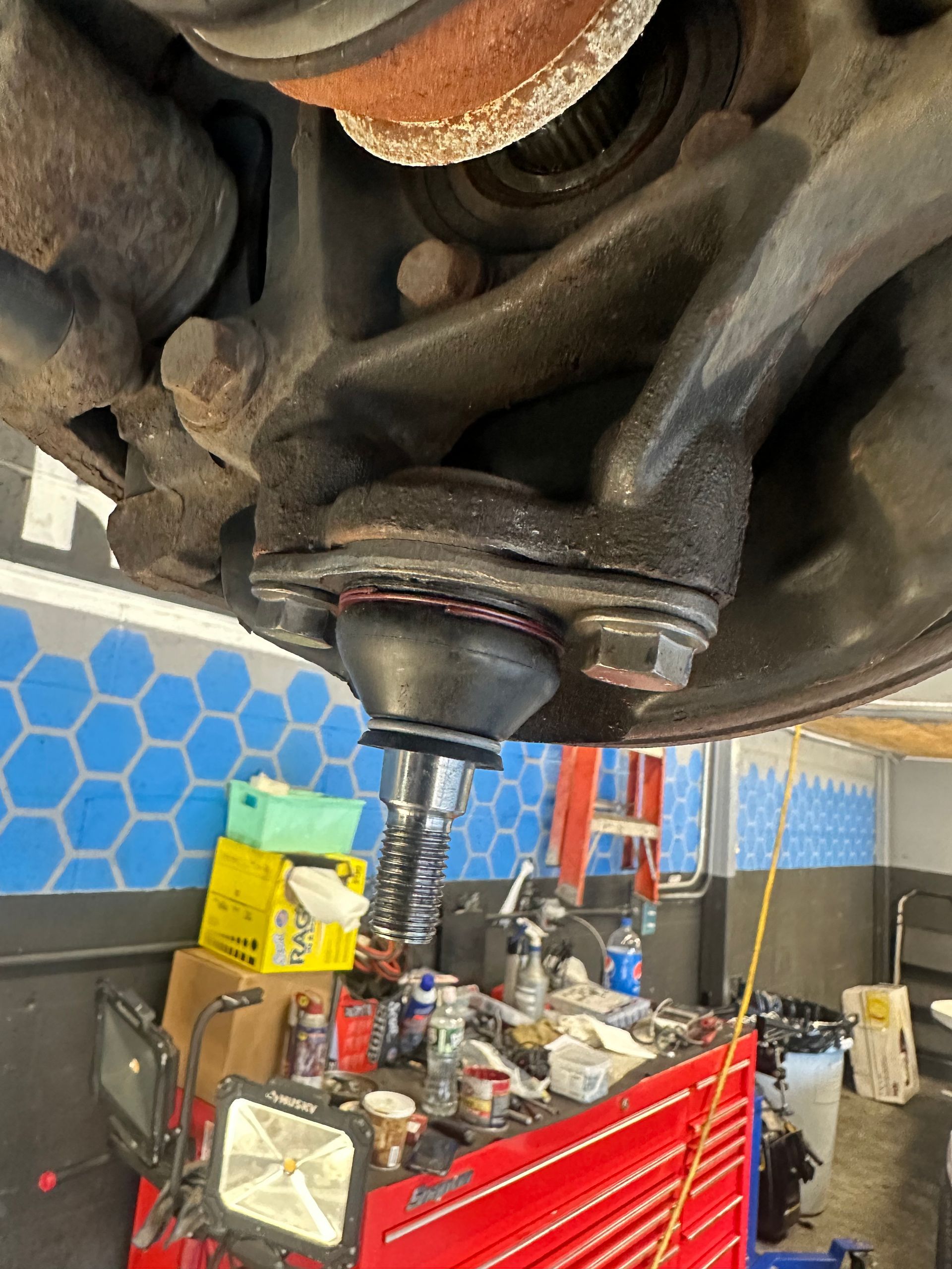 A ball joint is being removed from a car in a garage.