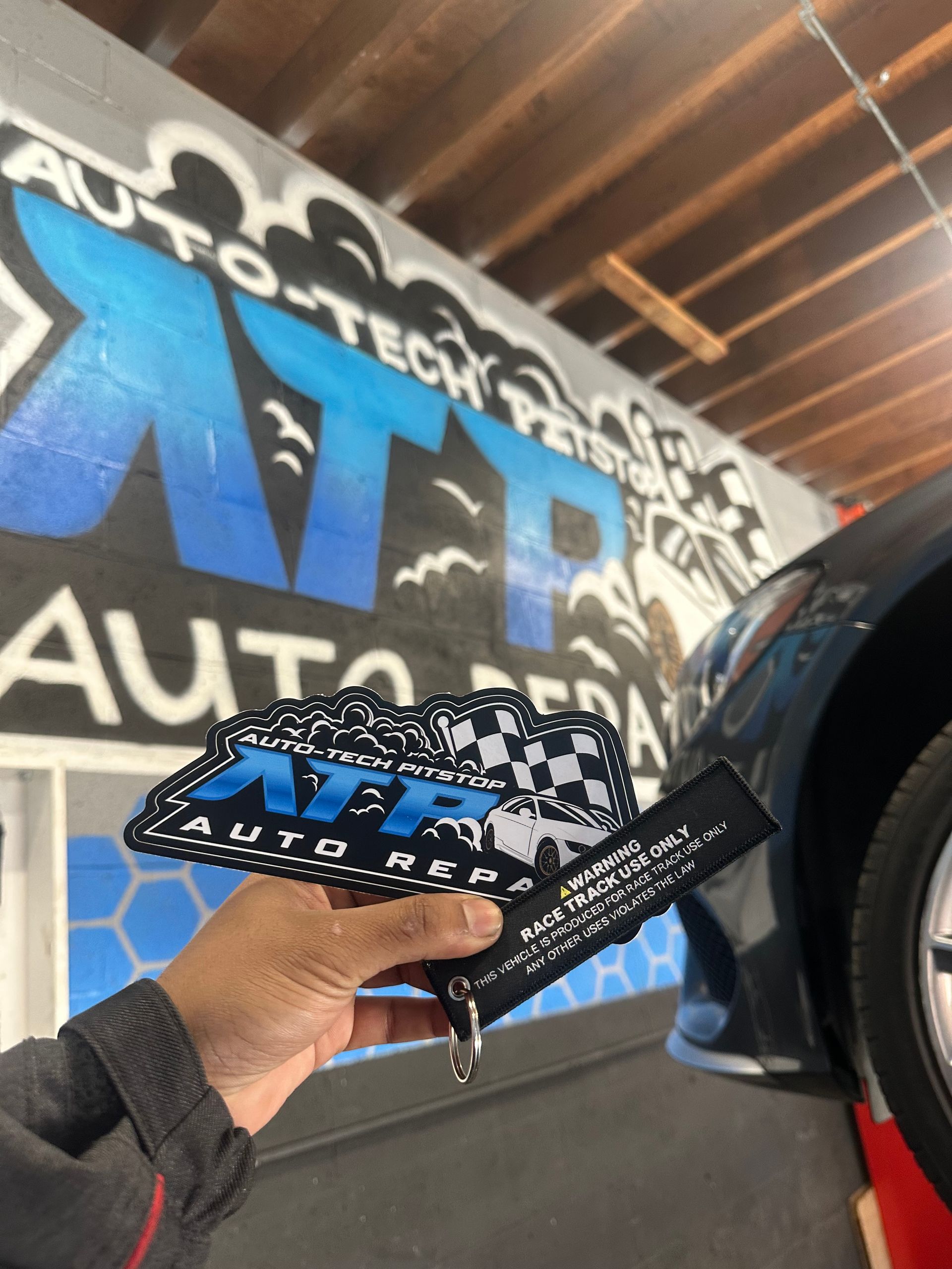 A person holding a bandana in front of a sign that says auto tech