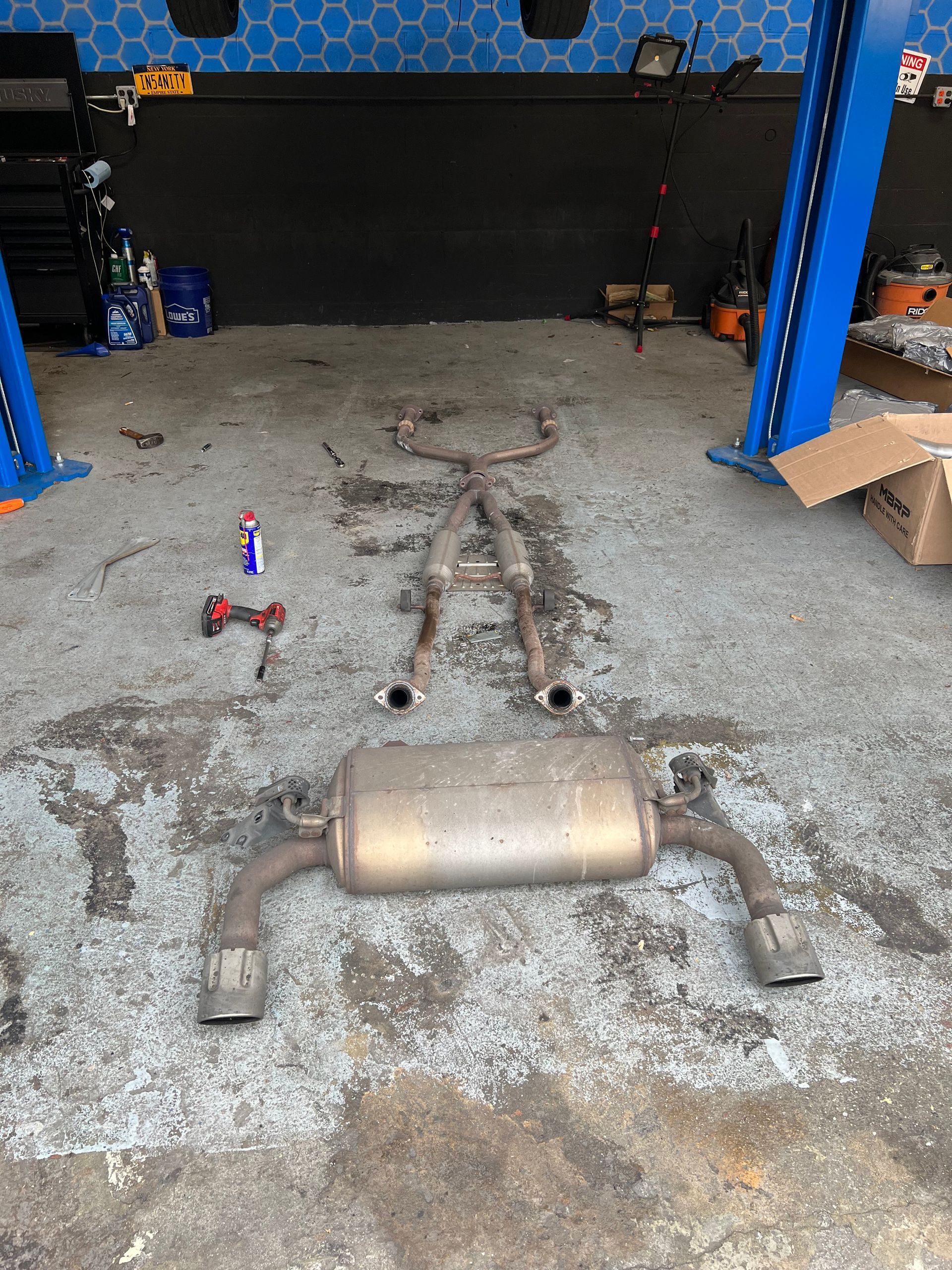 A exhaust pipe is laying on the ground in a garage.