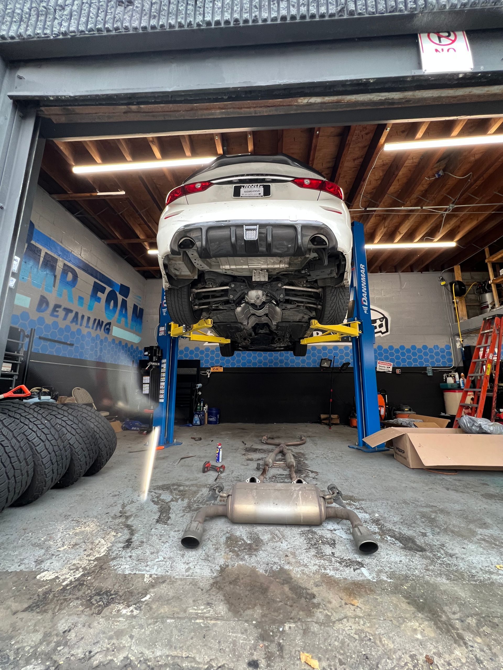 A car is sitting on a lift in a garage.