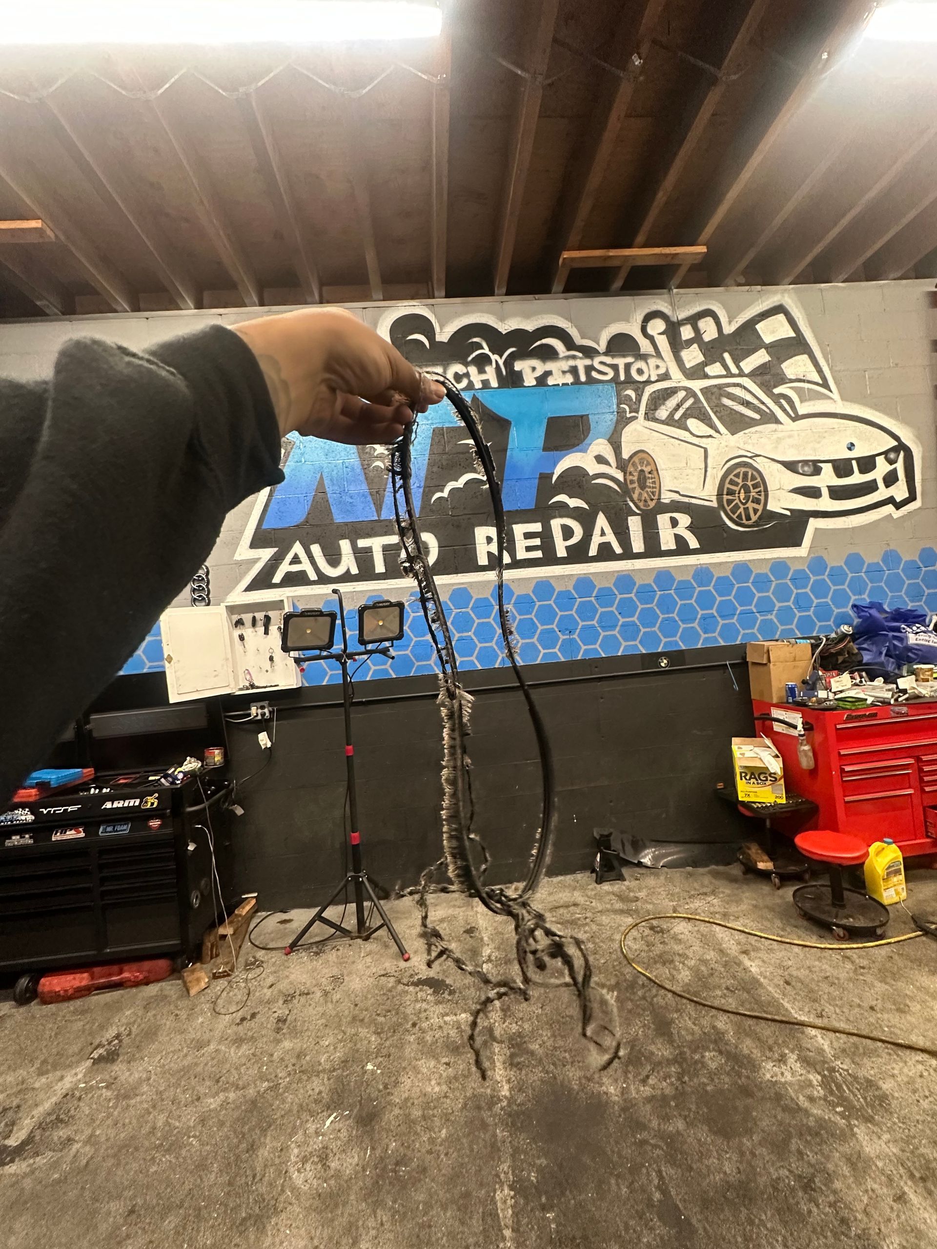 A person is holding a chain in front of a sign that says auto repair.