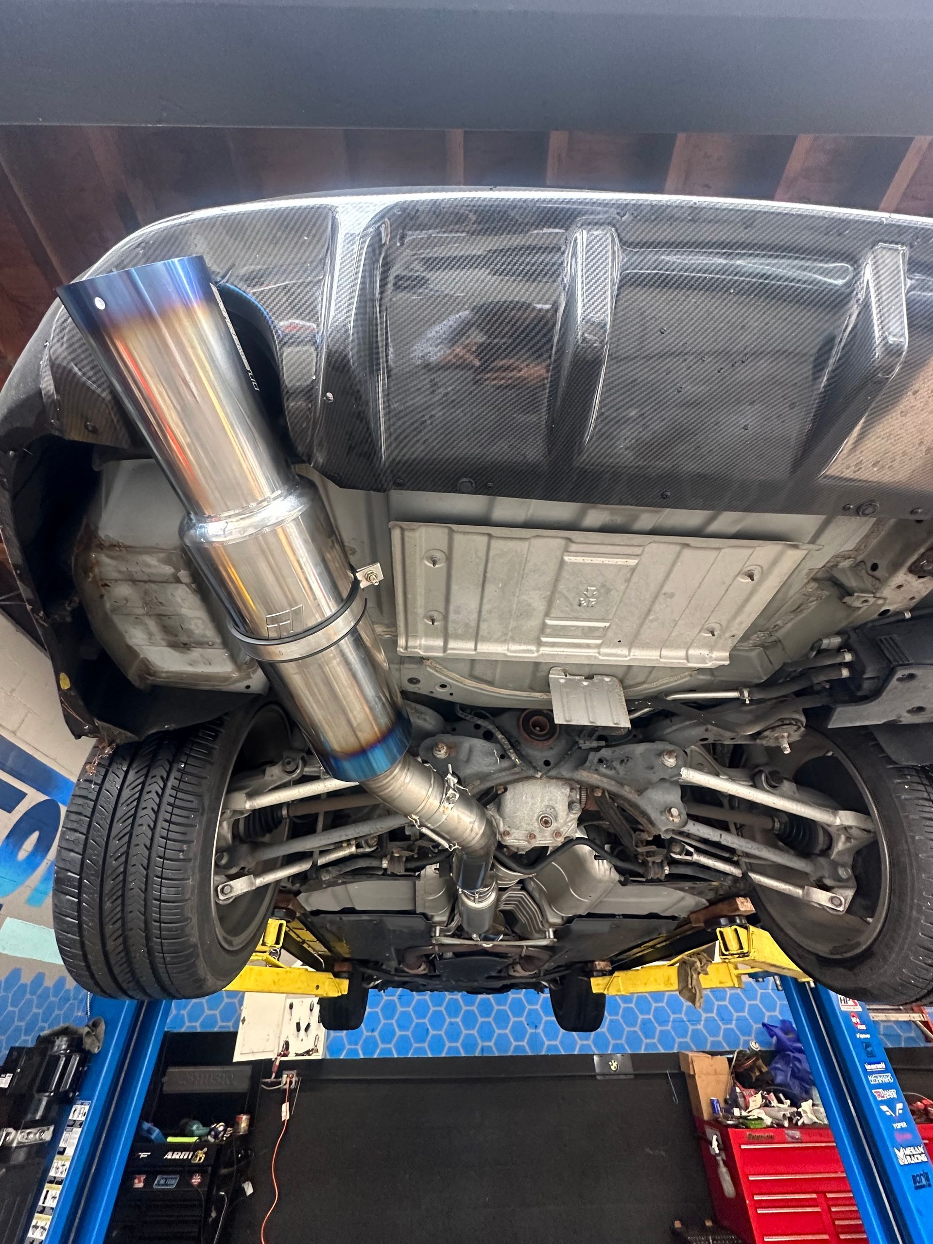 A car is sitting on a lift in a garage.