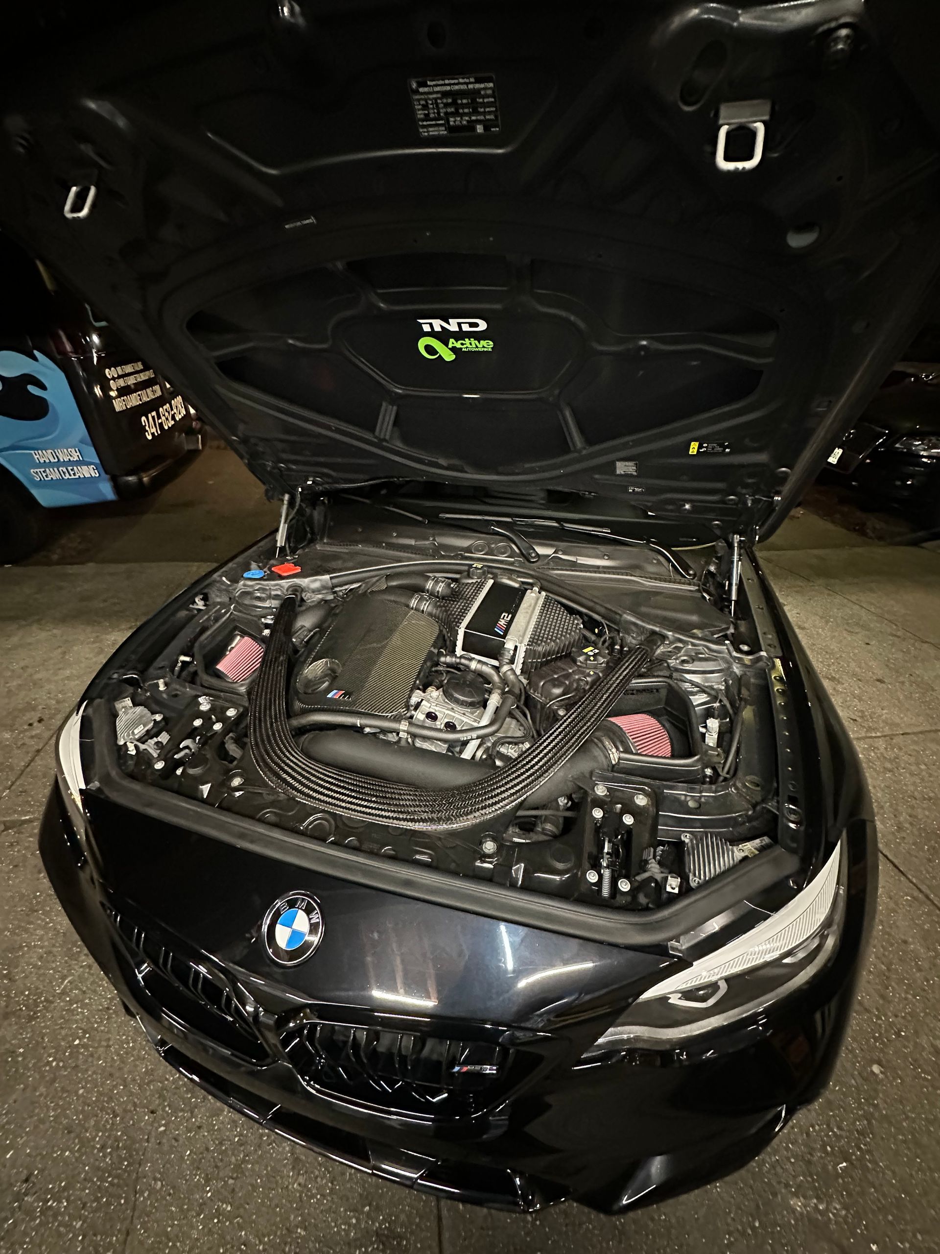 The hood of a black bmw is open and the engine is visible.