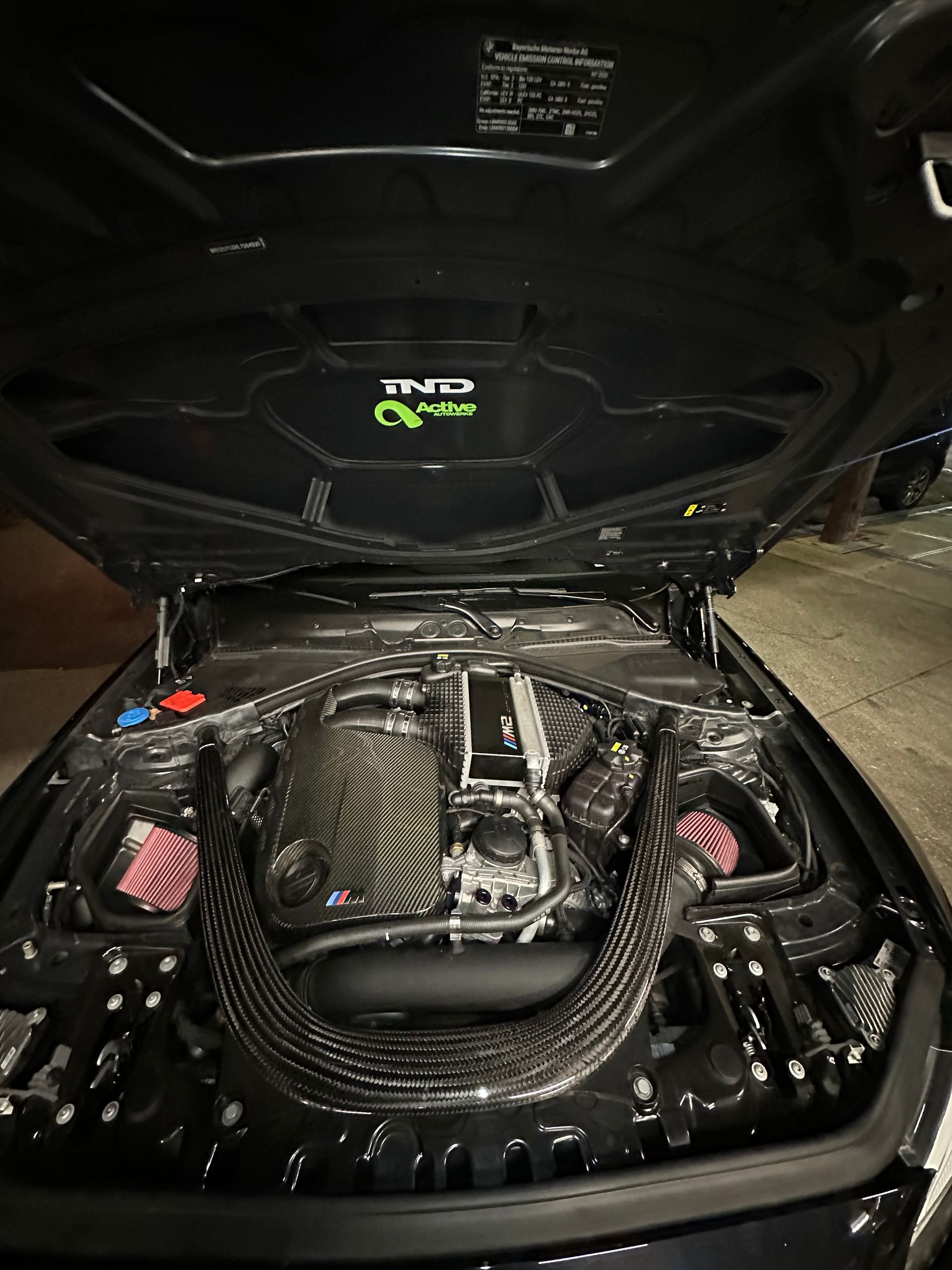 The hood of a black car is open and shows the engine.