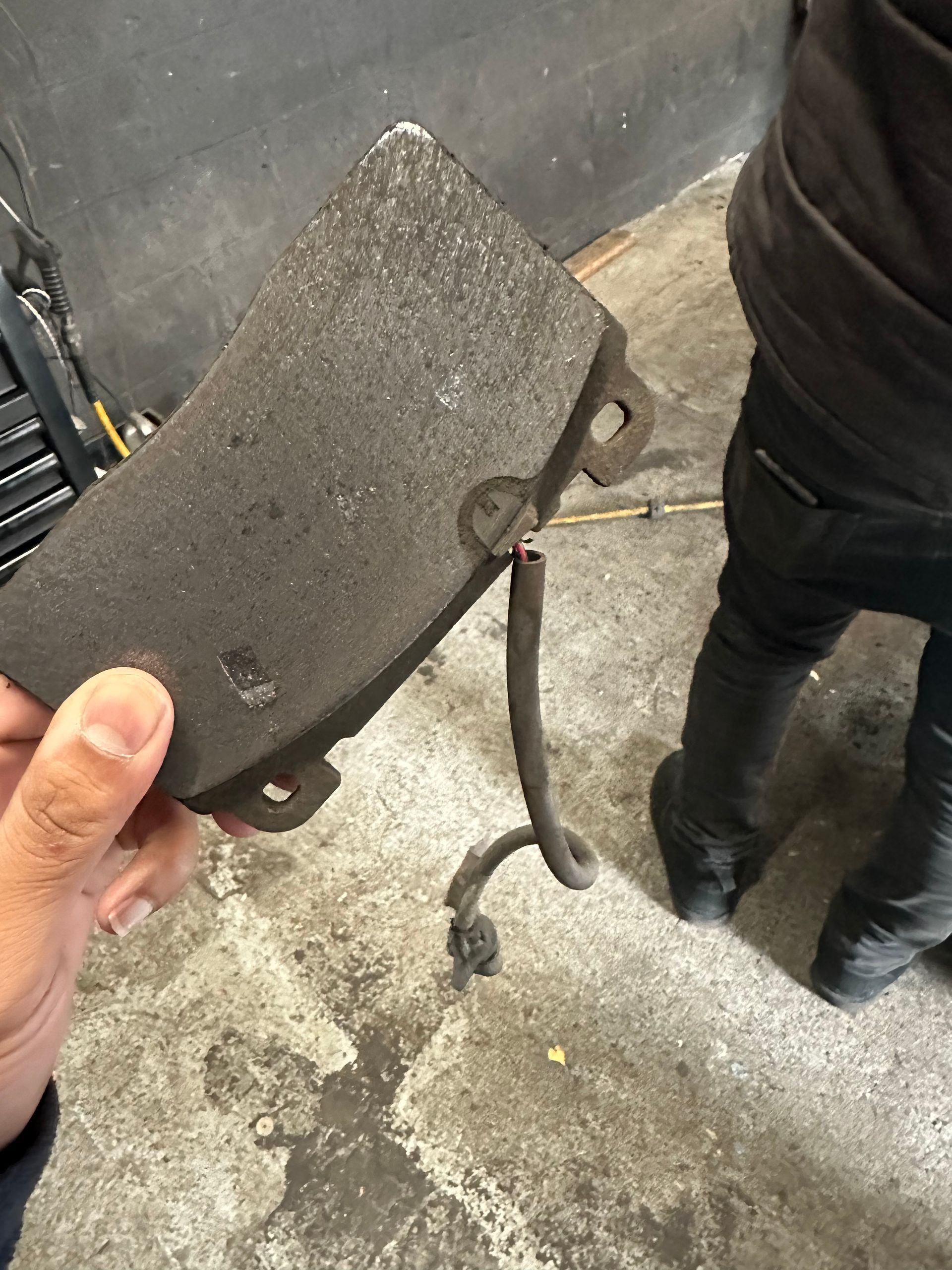 A person is holding a brake pad in their hand.